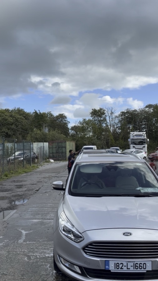 A silver Ford Galaxy on the wet forecourt after a wash